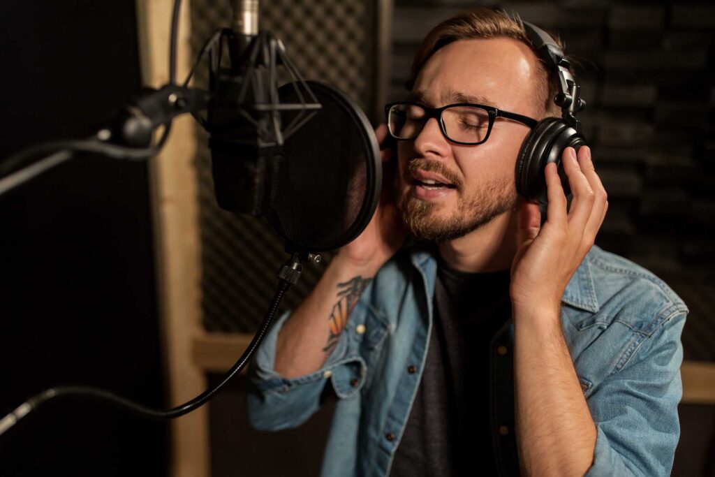 man-with-headphones-singing-at-recording-studio-PHLVNYL.jpg